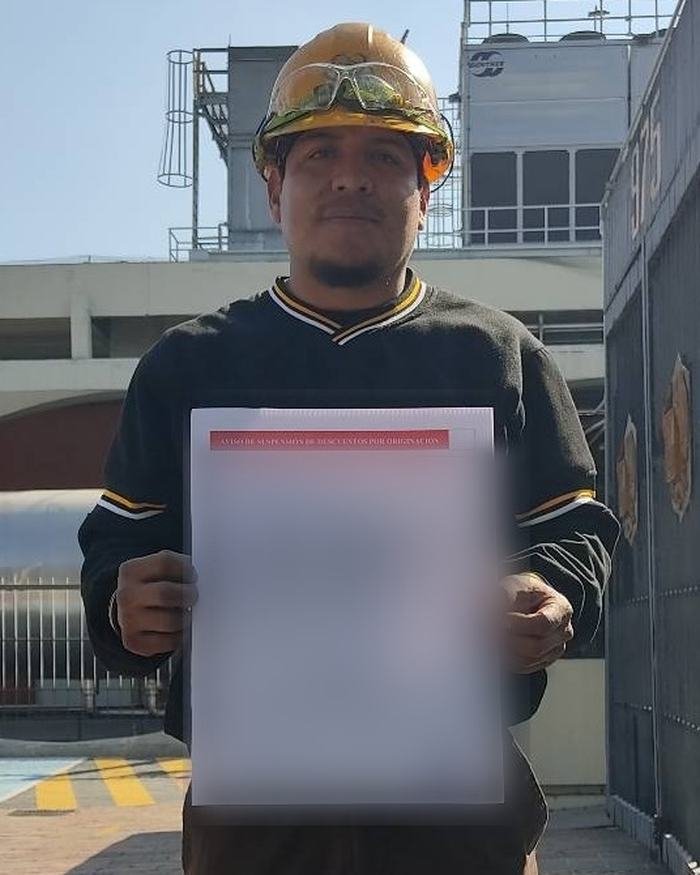 Un trabajador con casco sostiene el documento de su crédito, ya resuelto